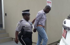 Clifton John being escorted from teh Magistrate's Court.