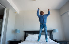 A young African boy enjoys jumping on the bed