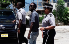 Convicted post-hurricane looter, Shamoii Dagou (centre) being escorted by police.