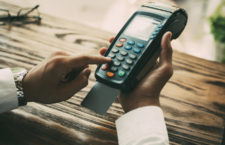 Unrecognizable businessman spending money in cafe. Male manager holding credit card reader with inserted card. Close-up of male hands using modern machine. Cashless payment concept