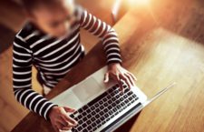 Young ethnic black girl sitting at the dining table at home typing on a laptop computer, high angle view looking down on the keyboard (Young ethnic black girl sitting at the dining table at home typing on a laptop computer, high angle view looking dow