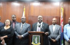 Premier addressing the nation with member of the VIP Government.