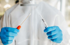Doctor in protective suit opening sterile packaging Of tube and swab to take sample on Coronavirus (Corvid19)