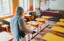 Man in protective suit disinfecting school building