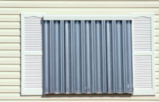 Hurricane protection corrugated metal panels installed on tropical home. (Not an exact storm shutter manufactured by local company, Scaffco Shutters)