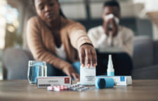 Cropped shot of a young couple sitting together at home and feeling sick while taking their medication
