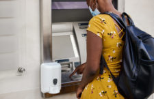 African woman uses ATM machine in the city during coronavirus pandemic.