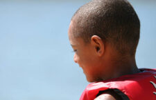 Young boy at the lake in life jacket