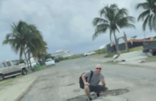 This image of a tourist posing in a pothole has gone viral on social media.